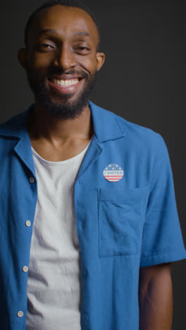 Vertical-Video-Portrait-Of-Shot-Of-Smiling-Man-With-I-Voted-Sticker-On-Shirt-In-American-Election